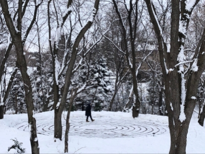 Woman walking on a snowy labyrinth.